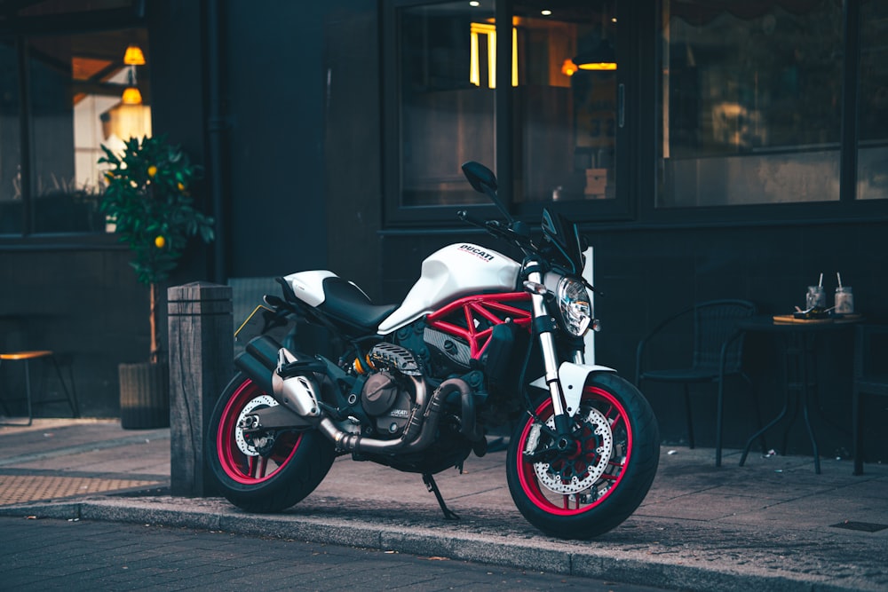 white and black sports bike parked on sidewalk during night time