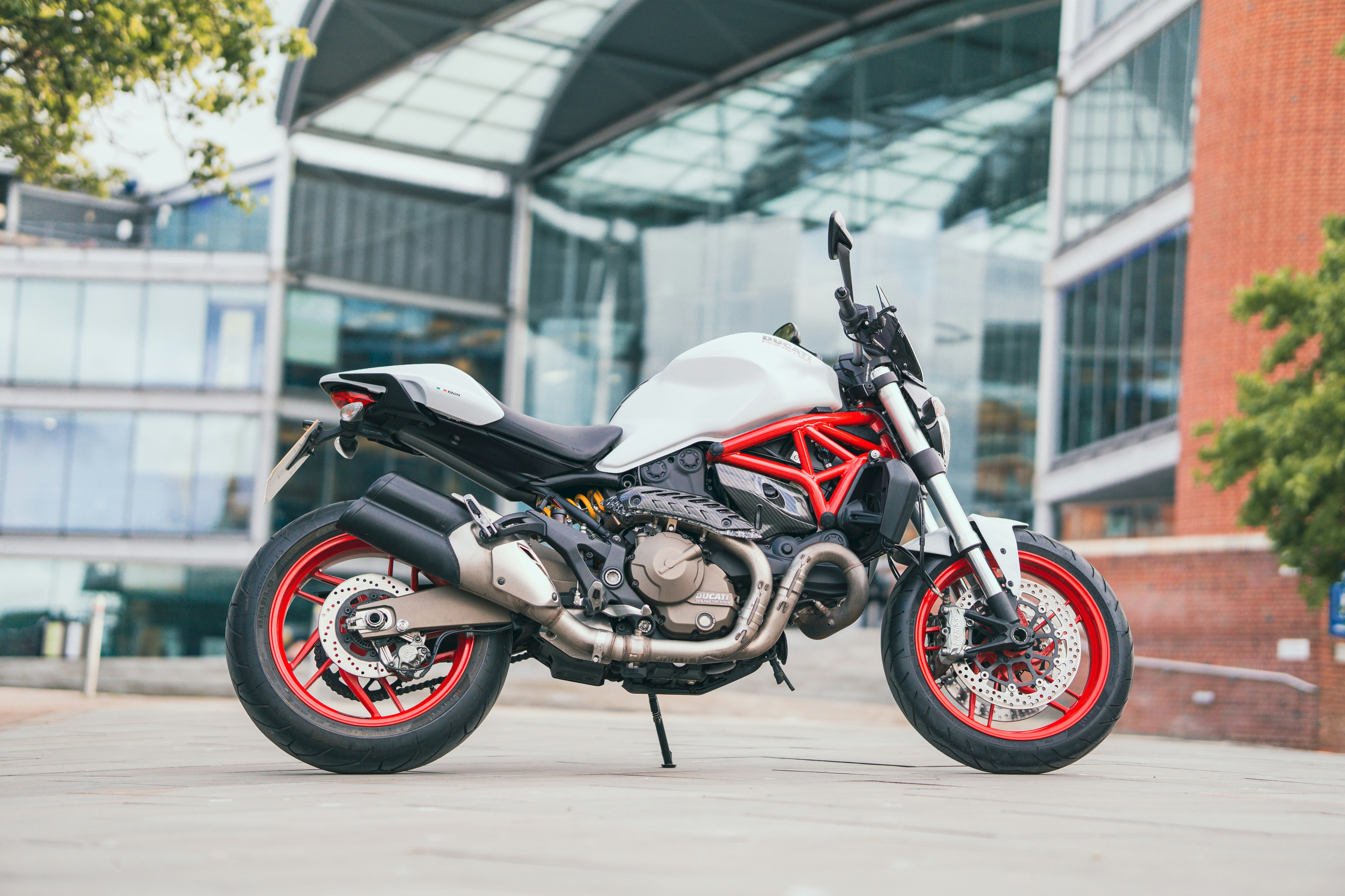 Red and white Ducati Monster 821 motorcycle outside of a large modern library