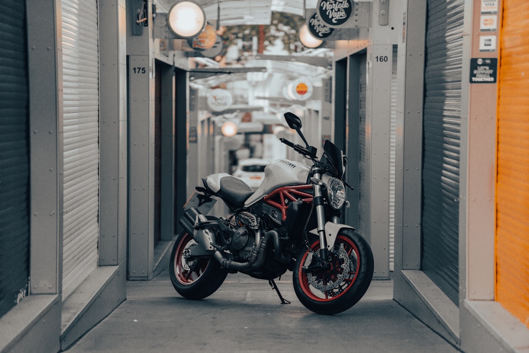 black and red naked motorcycle parked beside glass door