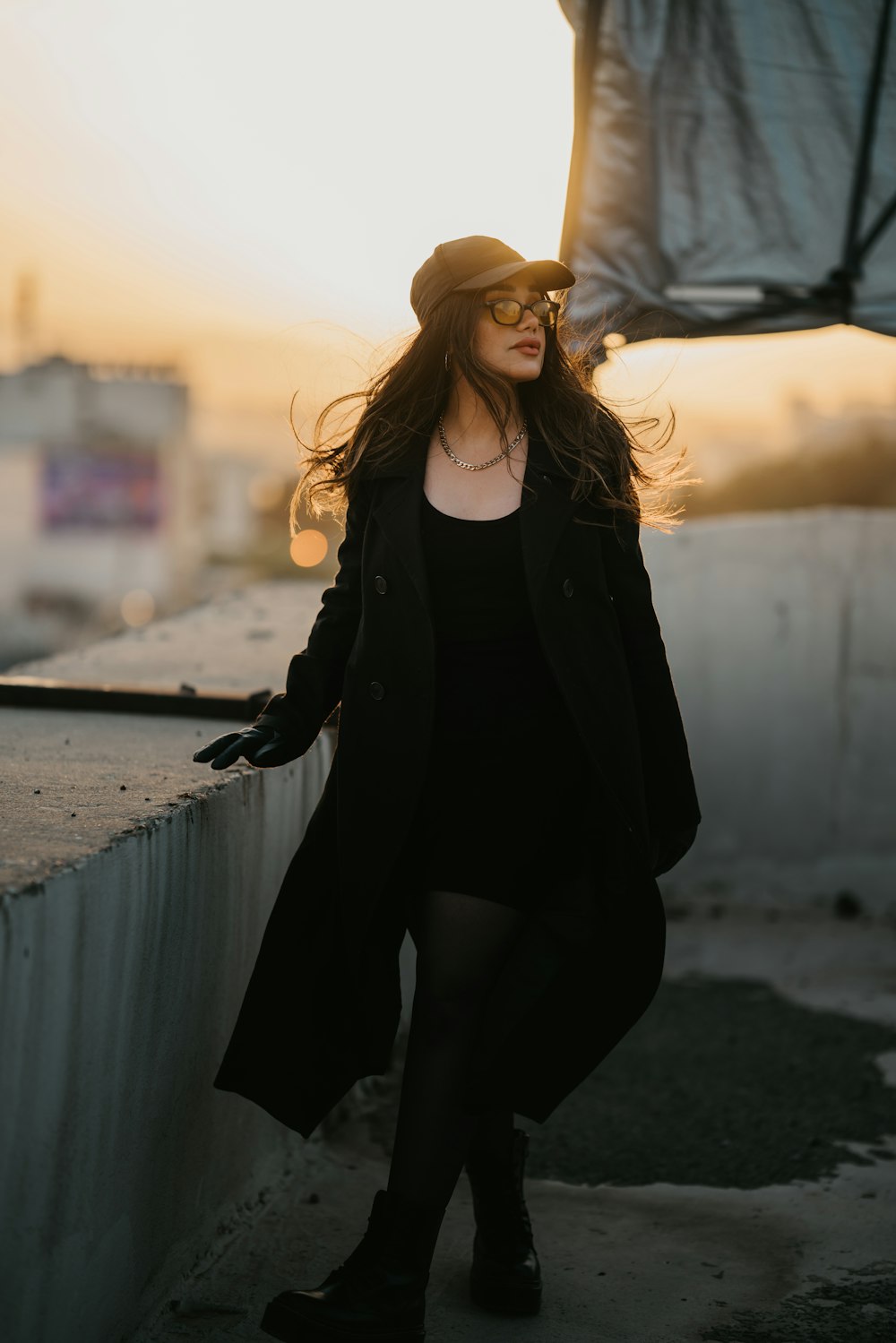 woman in black long sleeve dress and yellow sun hat standing on gray concrete pavement during