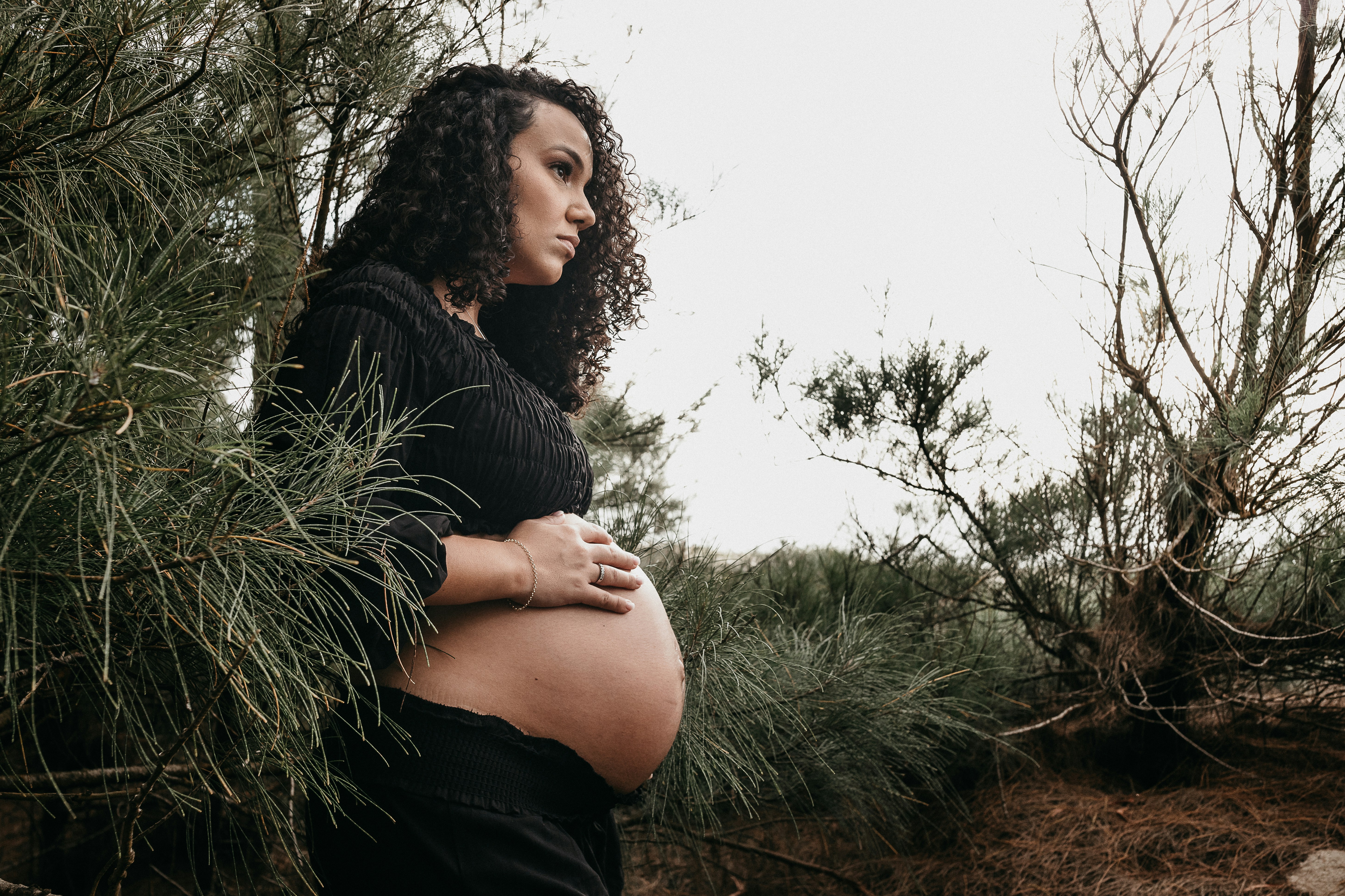 woman in black long sleeve shirt and black shorts sitting on brown wooden fence during daytime