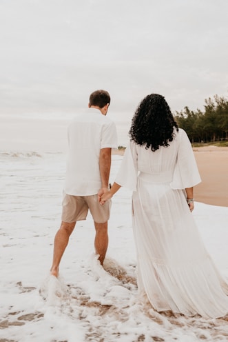 man and woman walking on beach during daytime