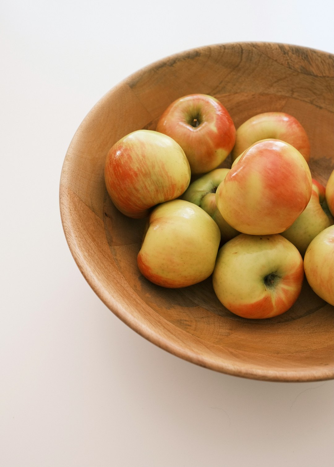 green and red apples on brown wooden bowl