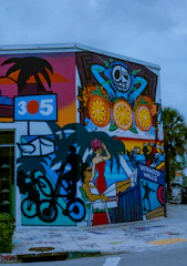 Photo of a sunlit Miami street corner with vivid graffiti and a young person wearing vibrant streetwear, embodying raw Florida energy.