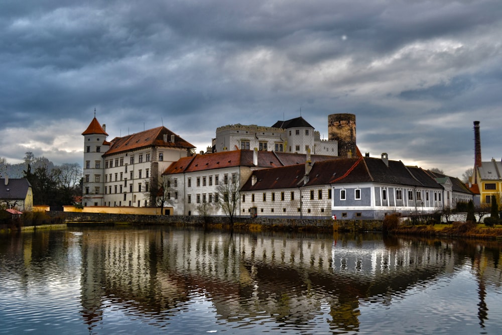 white and brown concrete building beside body of water under cloudy sky during daytime