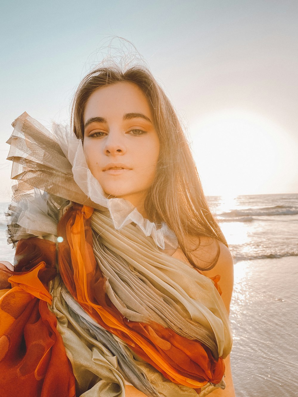 woman in orange dress standing on beach during daytime