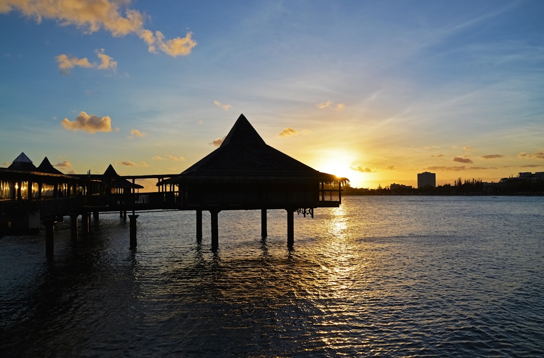 silhouette of gazebo on body of water during sunset