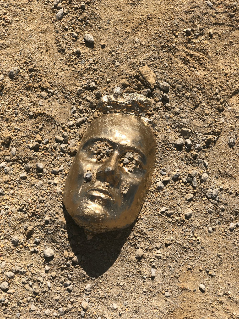 brown wooden face carved on brown soil