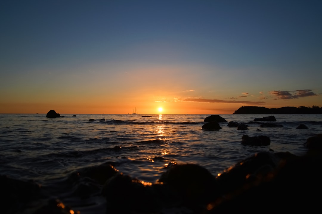 silhouette of rocks on sea during sunset