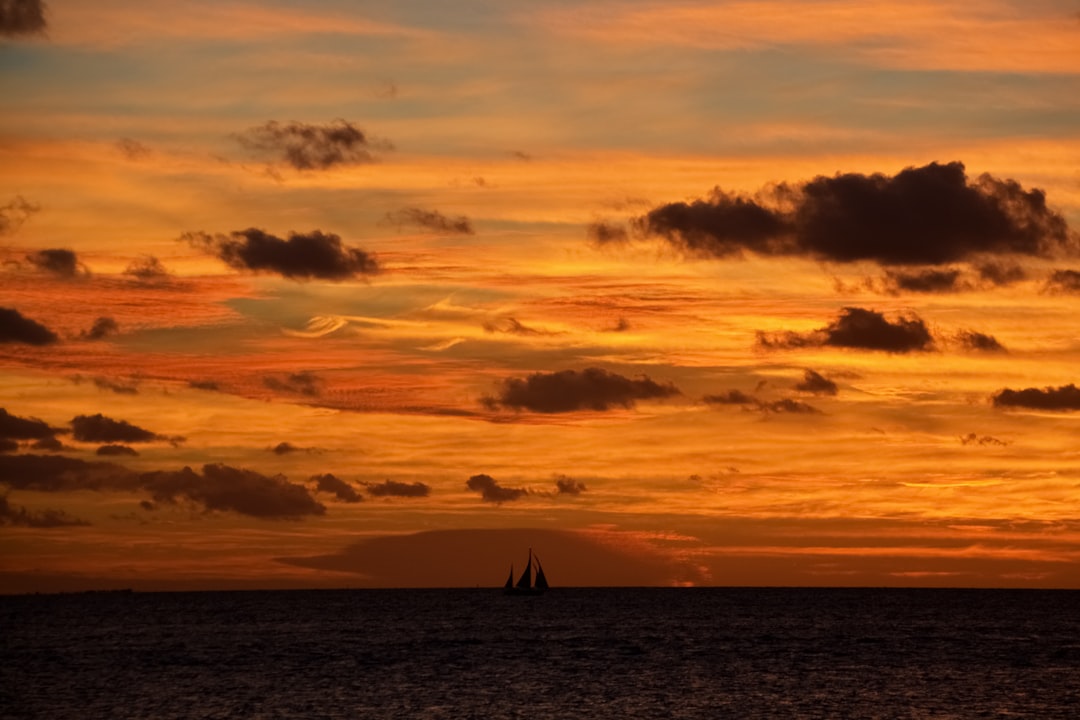 sailboat on sea under orange and blue sky
