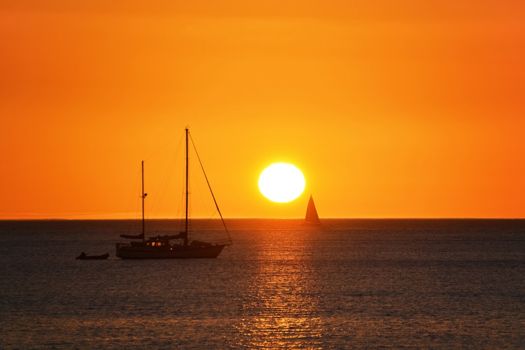 silhouette of boat on sea during sunset