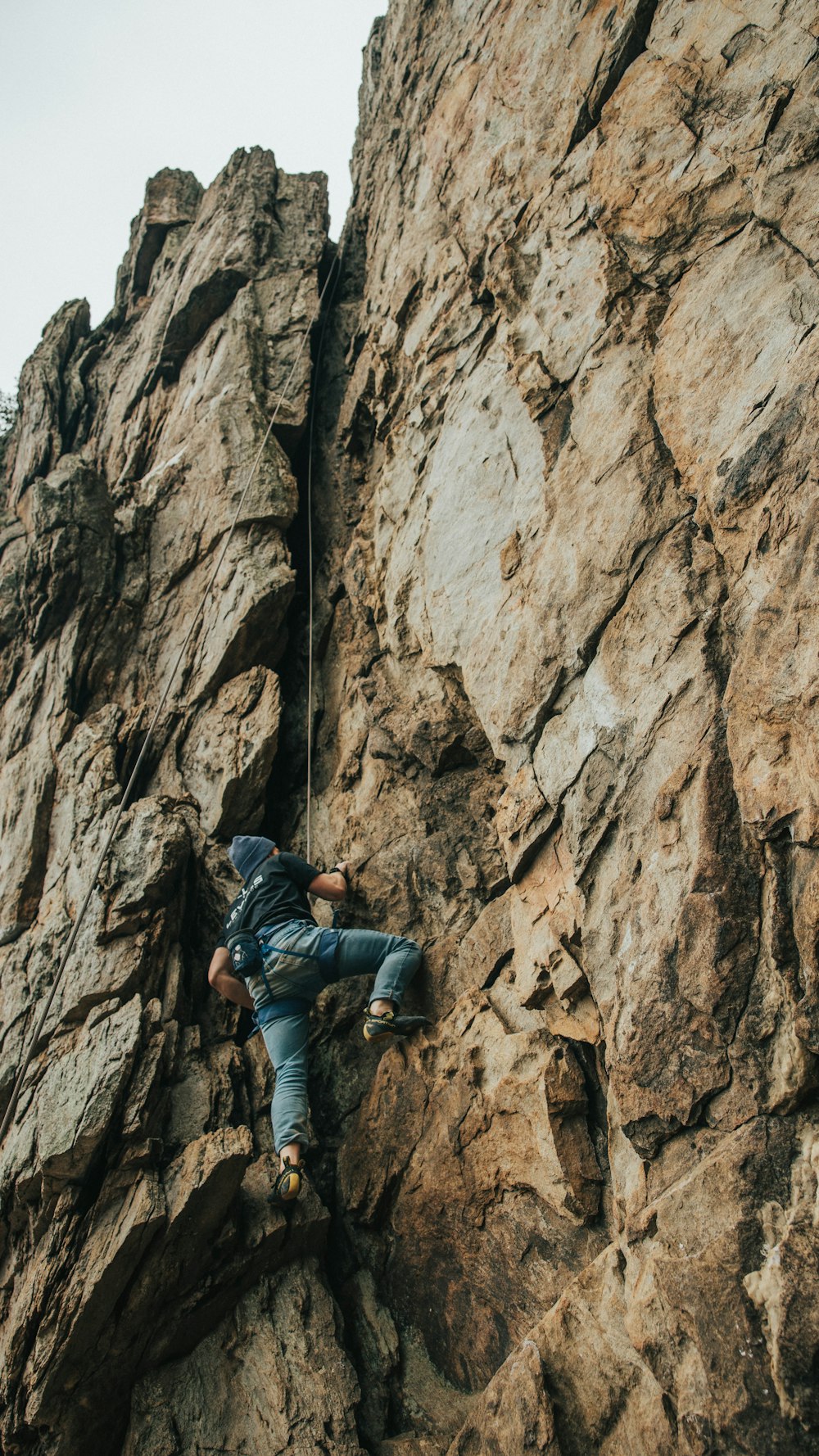 Hombre con chaqueta negra escalando en la montaña rocosa marrón durante el día