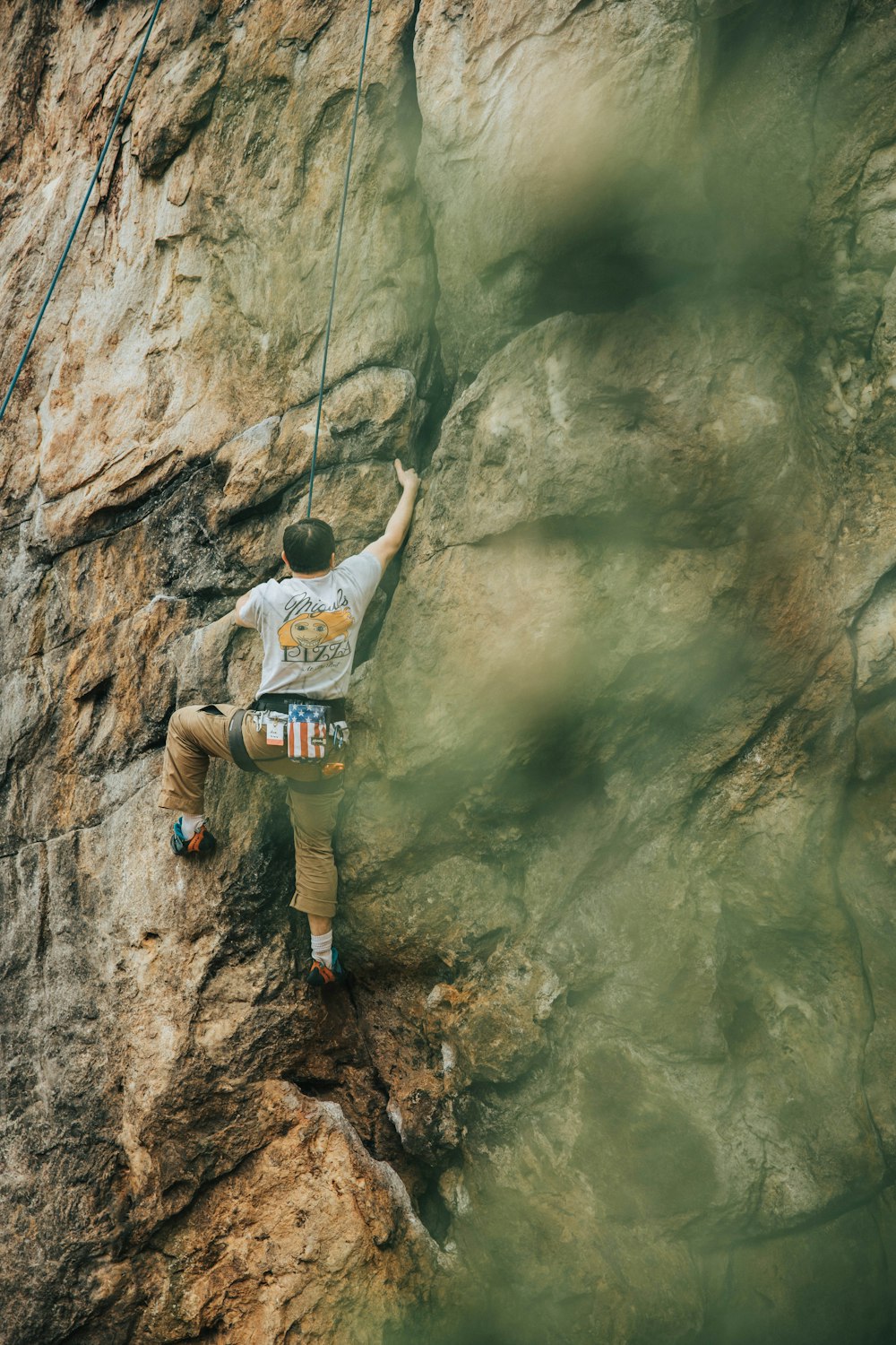 man in white t-shirt climbing on brown rock