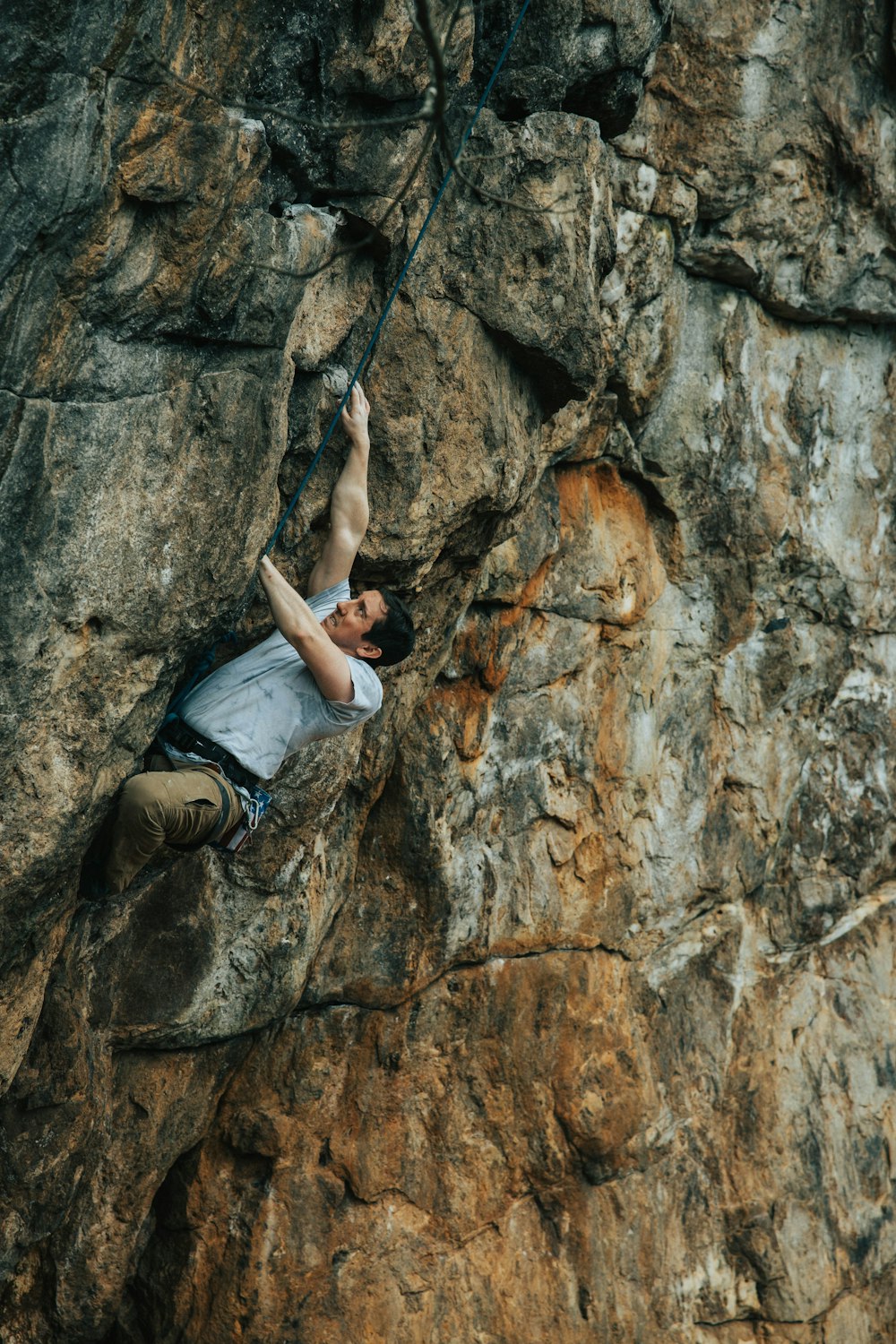 woman in gray tank top and black pants climbing on brown rock