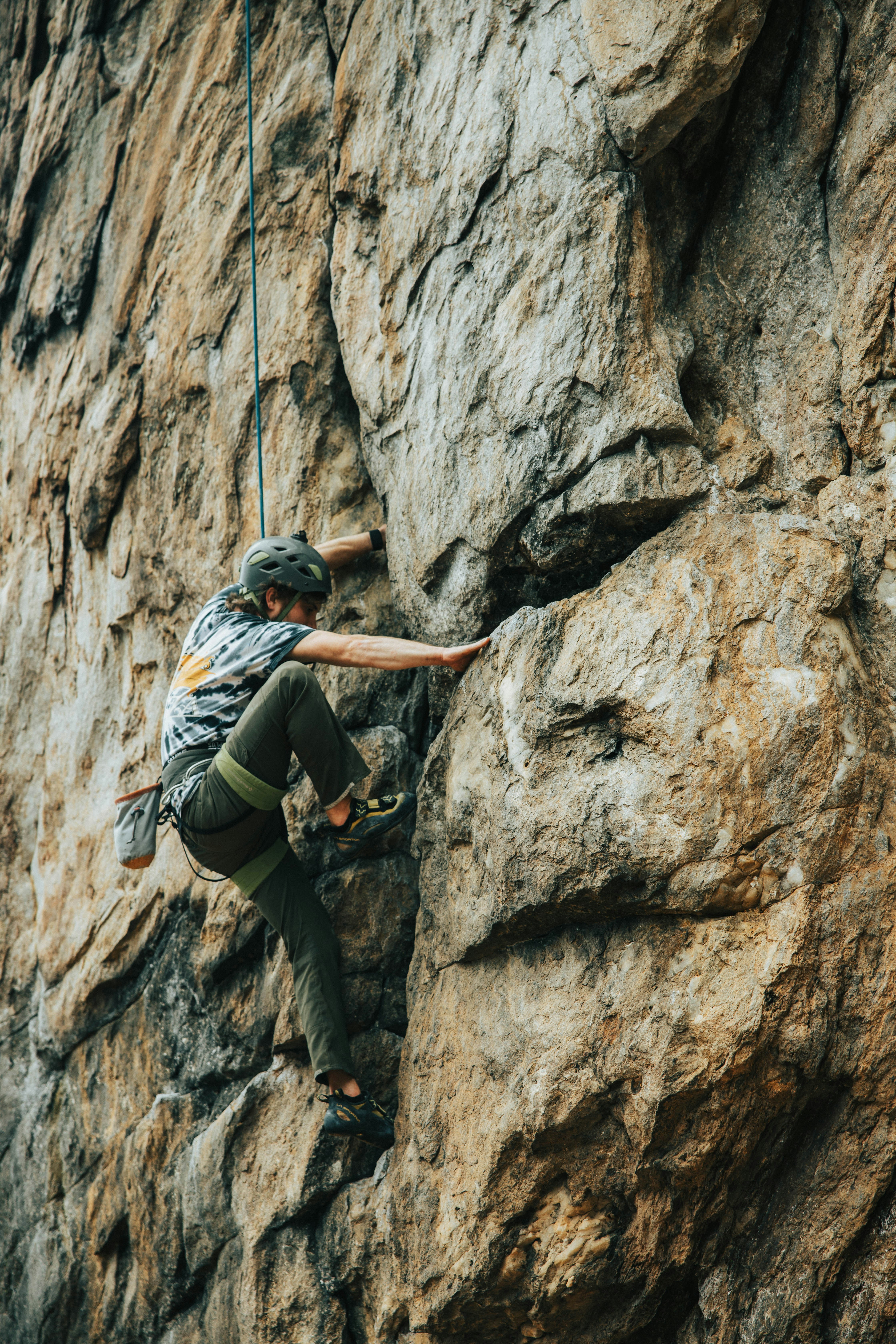 Man in black tshirt climbing on brown rock during daytime photo Free