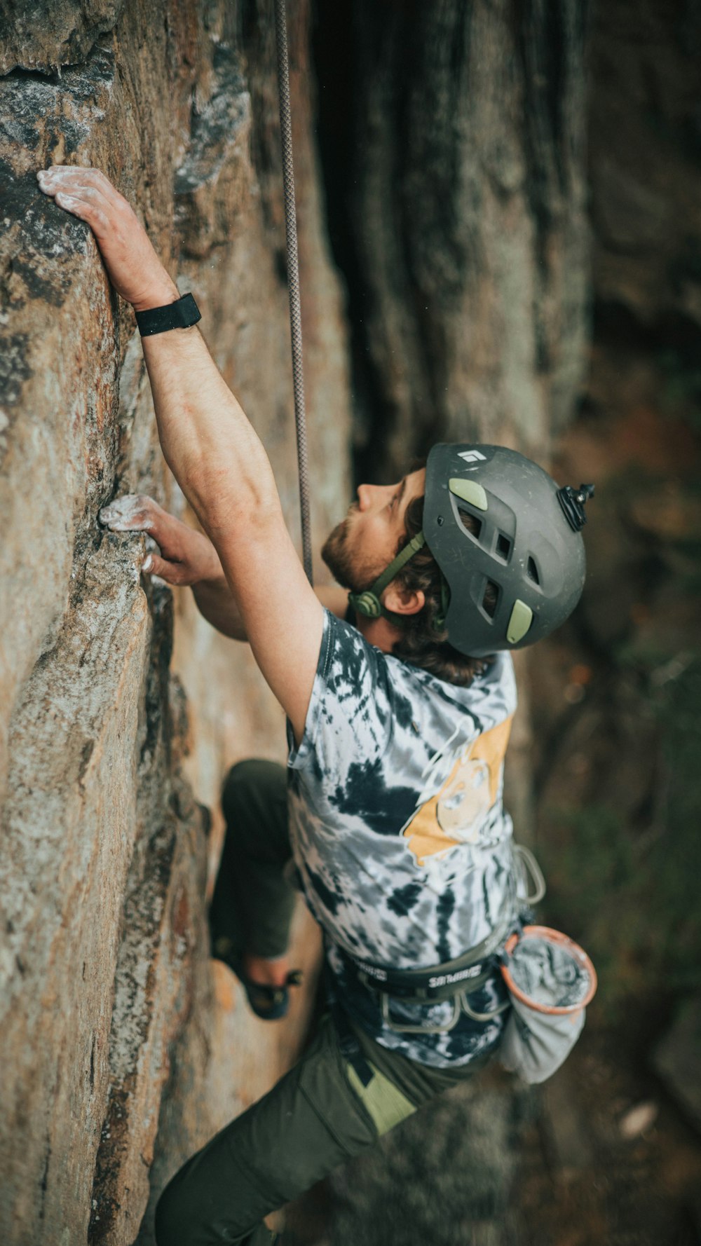 person in black and white skull print shirt wearing black and white helmet climbing on brown