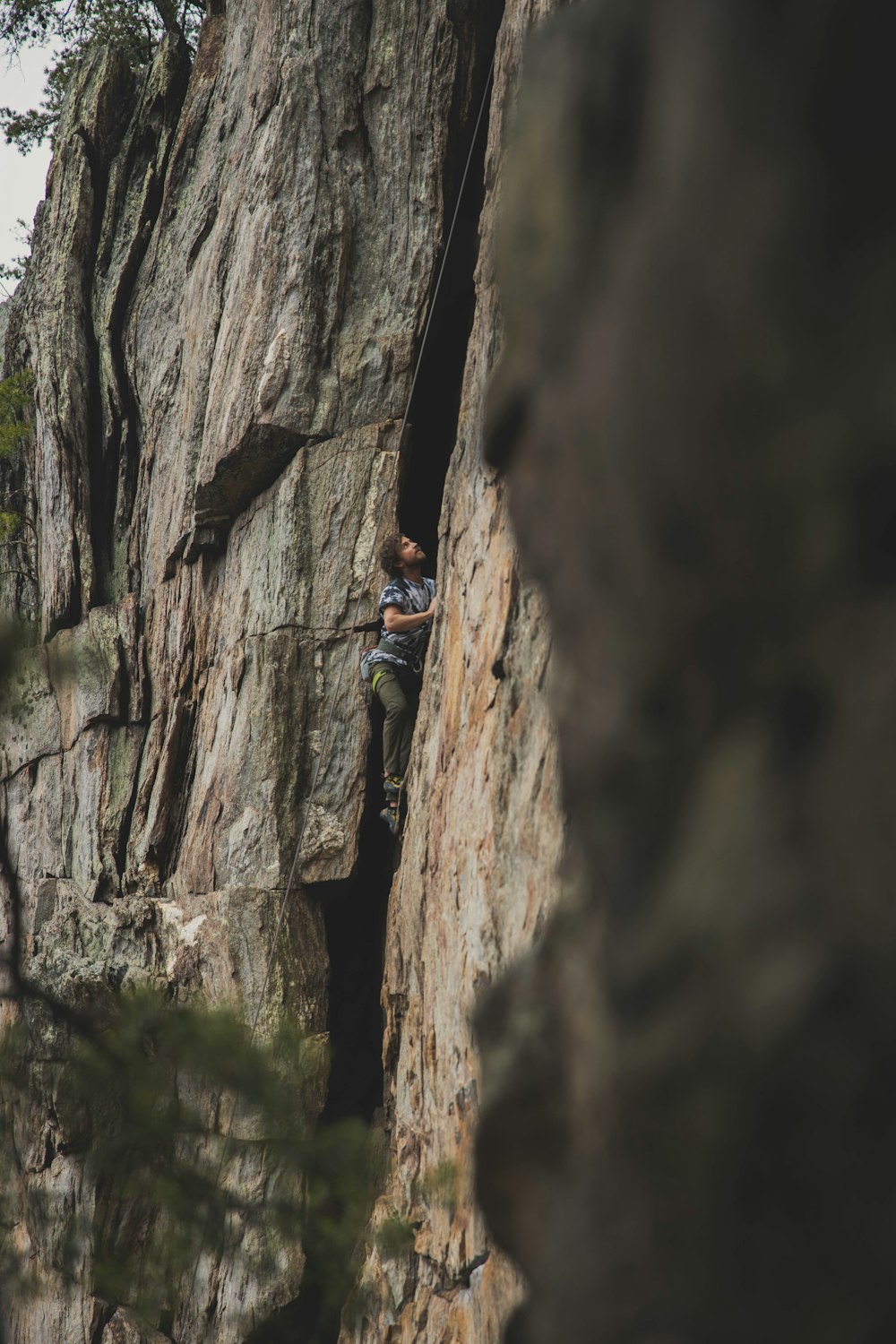 man in blue jacket climbing on brown rock mountain during daytime