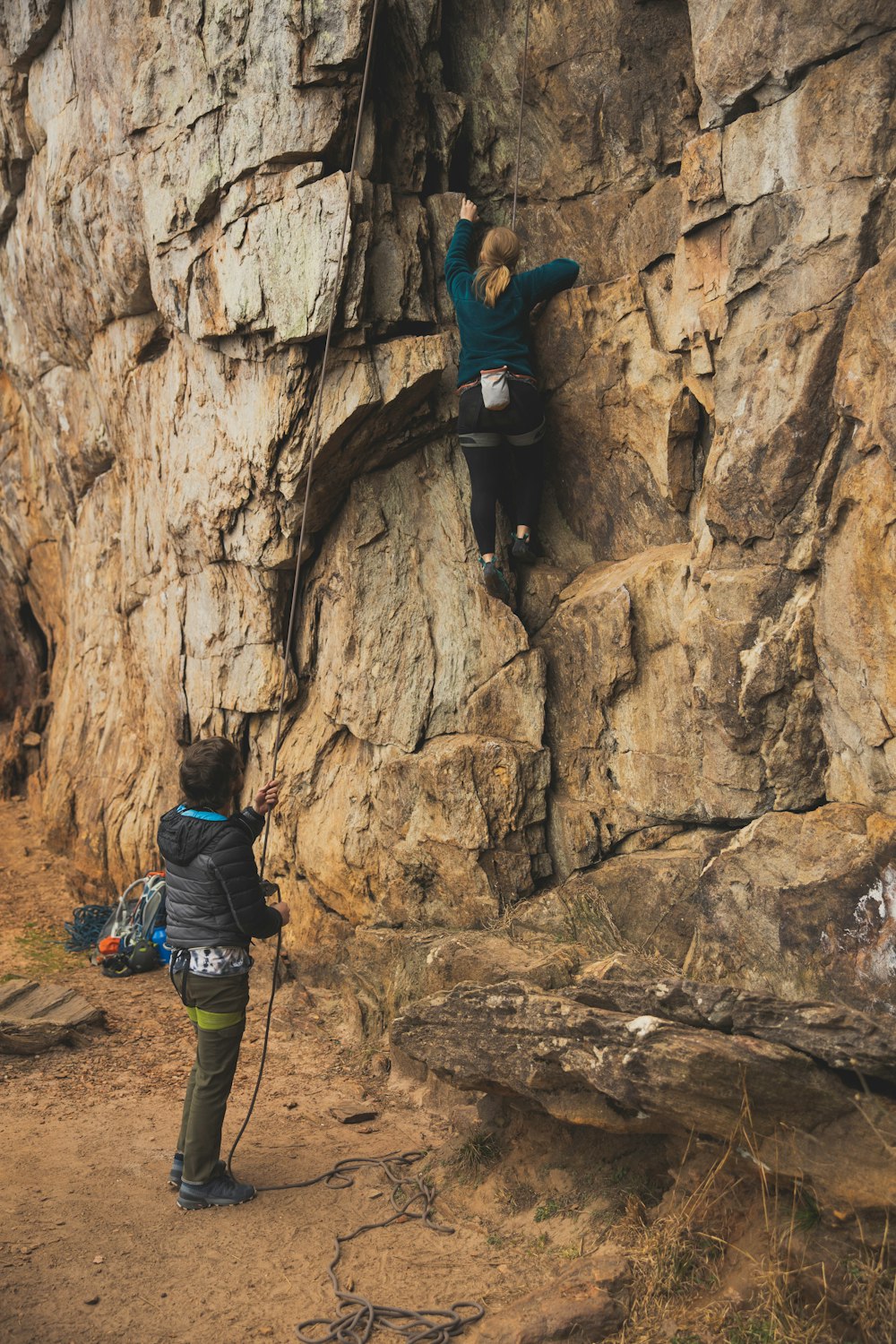 man in blue jacket climbing on brown rock formation during daytime