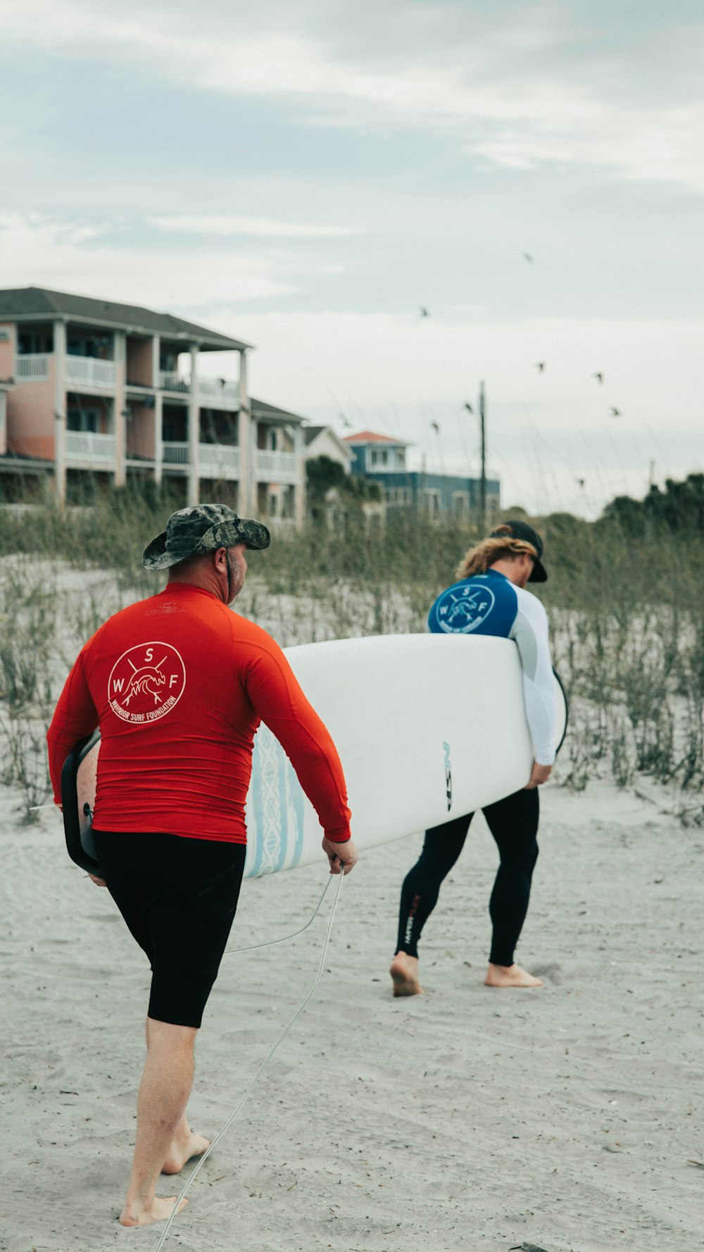 man in red long sleeve shirt holding white surfboard