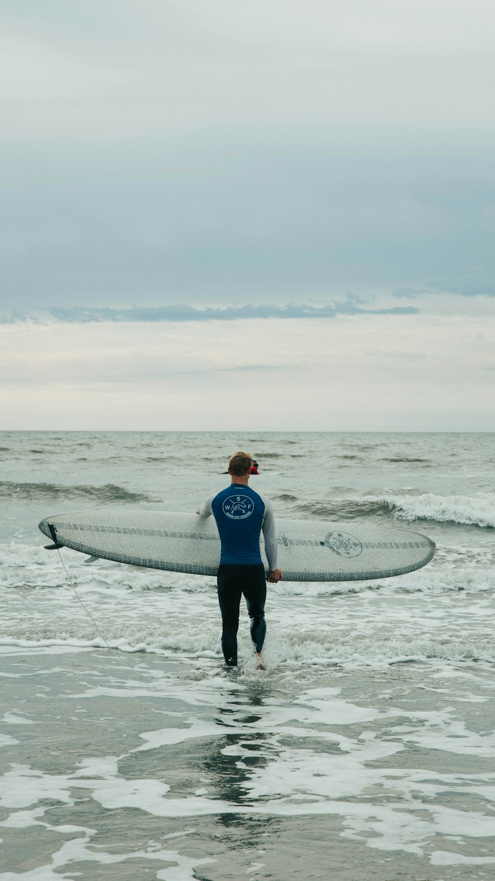 man and woman holding white surfboard walking on beach during daytime