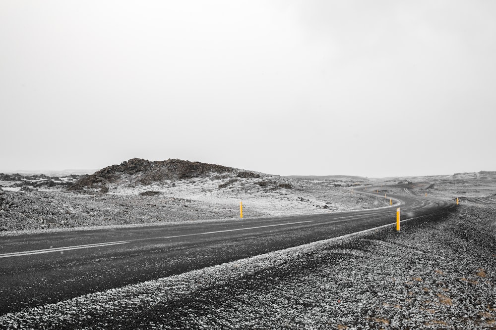 Route goudronnée noire au milieu d’un champ enneigé