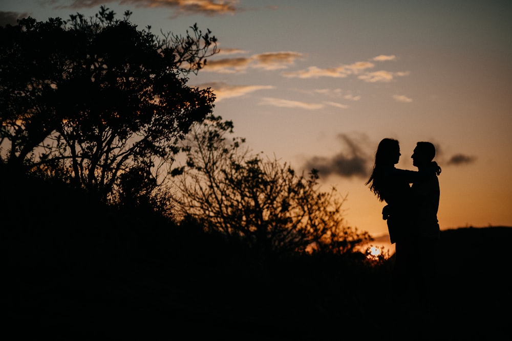 silhouette of person standing near tree during sunset