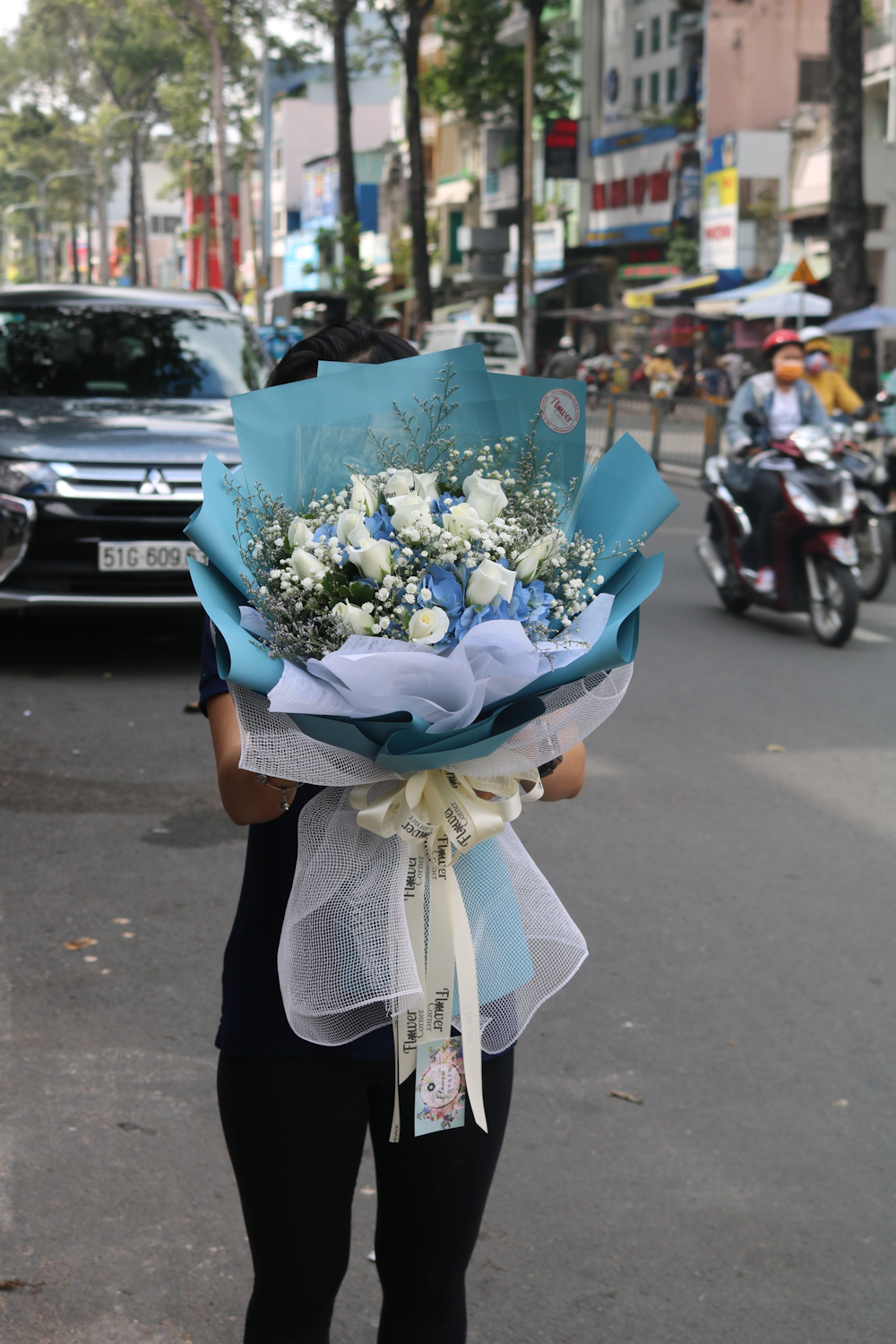 woman in black long sleeve shirt holding bouquet of flowers