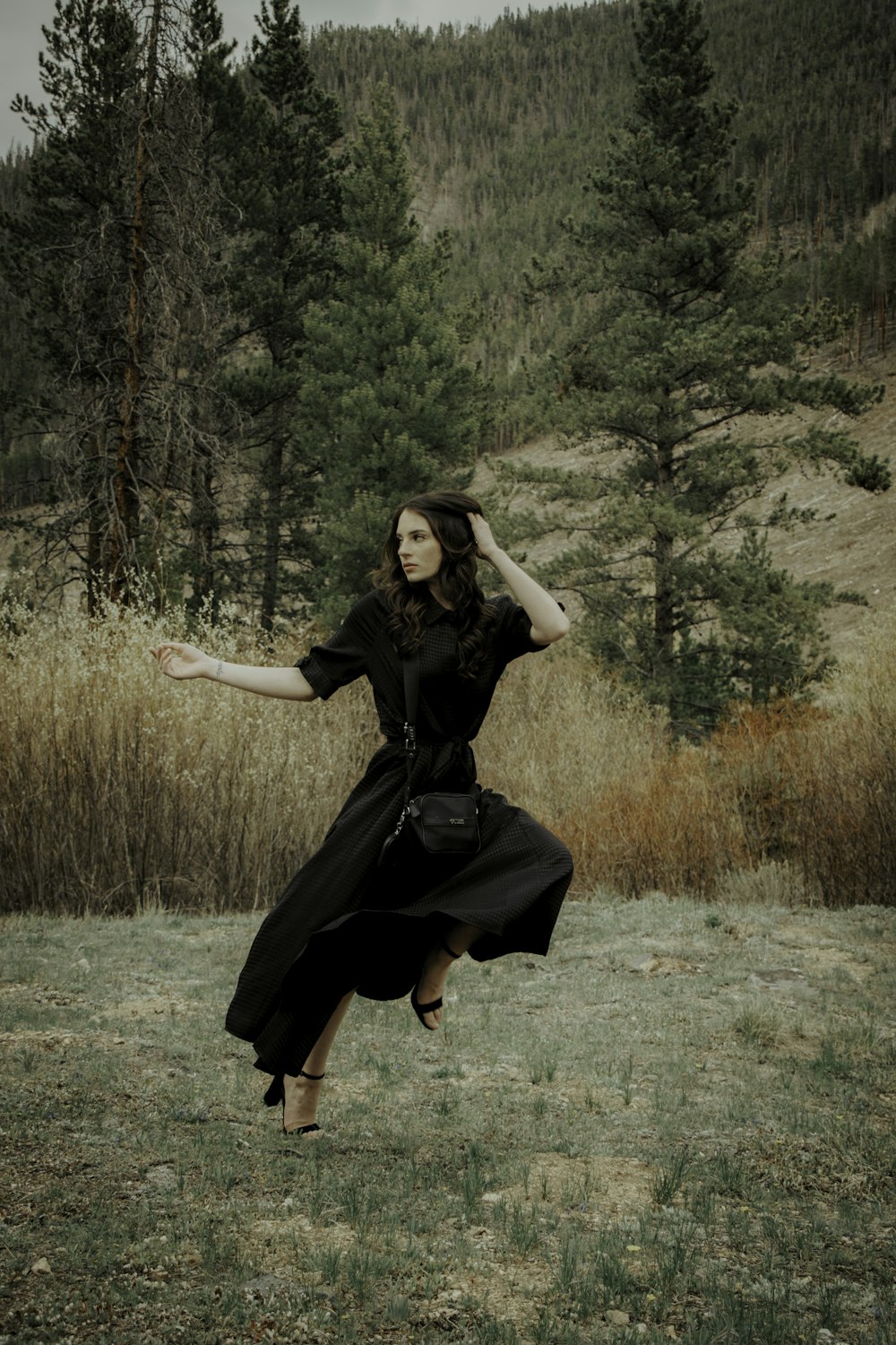 Mujer en vestido negro de pie en el campo de hierba verde durante el día
