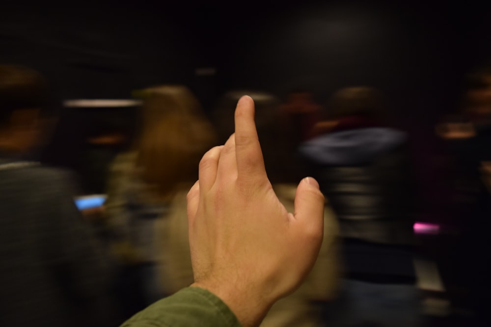 person in green long sleeve shirt showing right middle finger