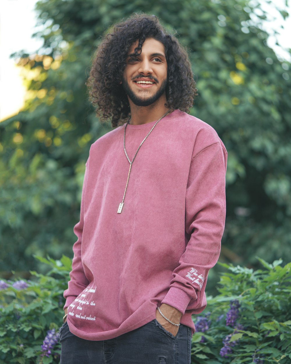 Femme en veste zippée rose debout près de la plante de feuilles vertes pendant la journée