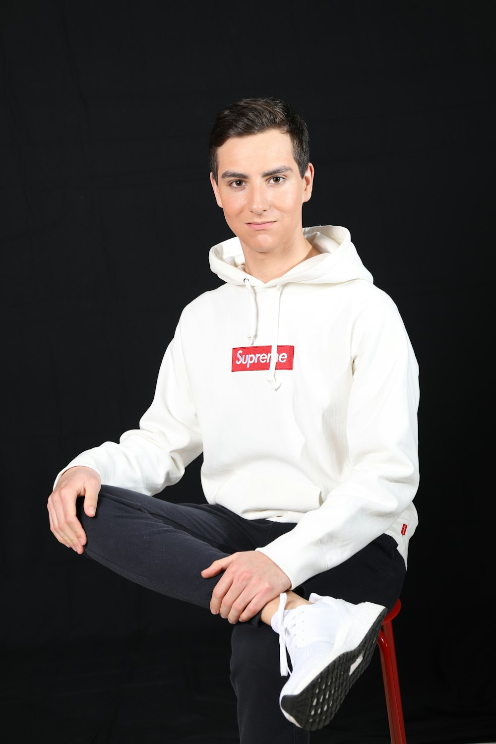 man in white pullover hoodie and black pants sitting on black chair