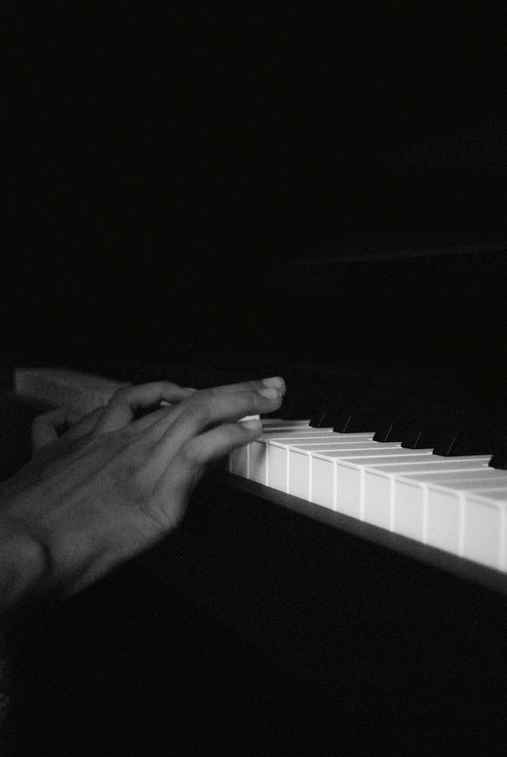 person playing piano in grayscale photography