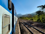 A luxury train winding through breathtaking mountain landscapes under clear blue skies.