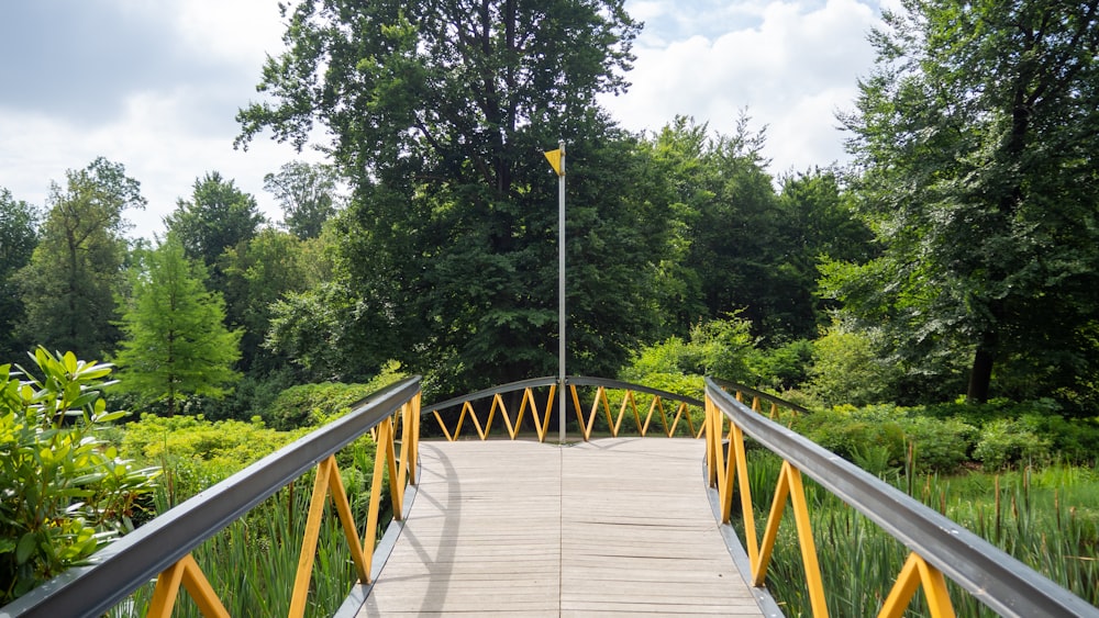 braune Holzbrücke tagsüber zwischen grünen Bäumen