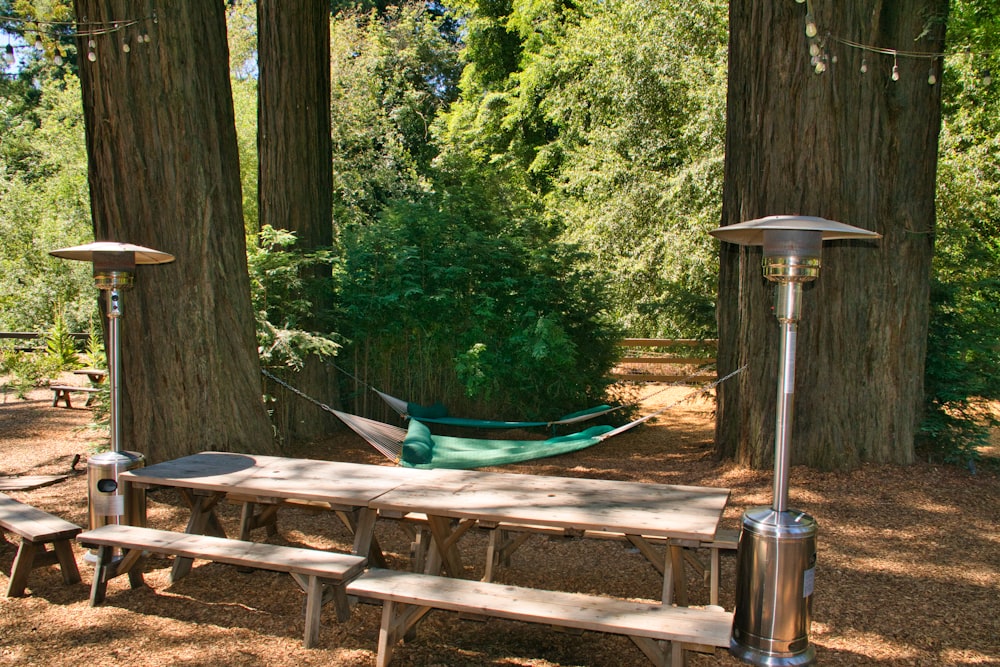 brown wooden picnic table near green trees during daytime