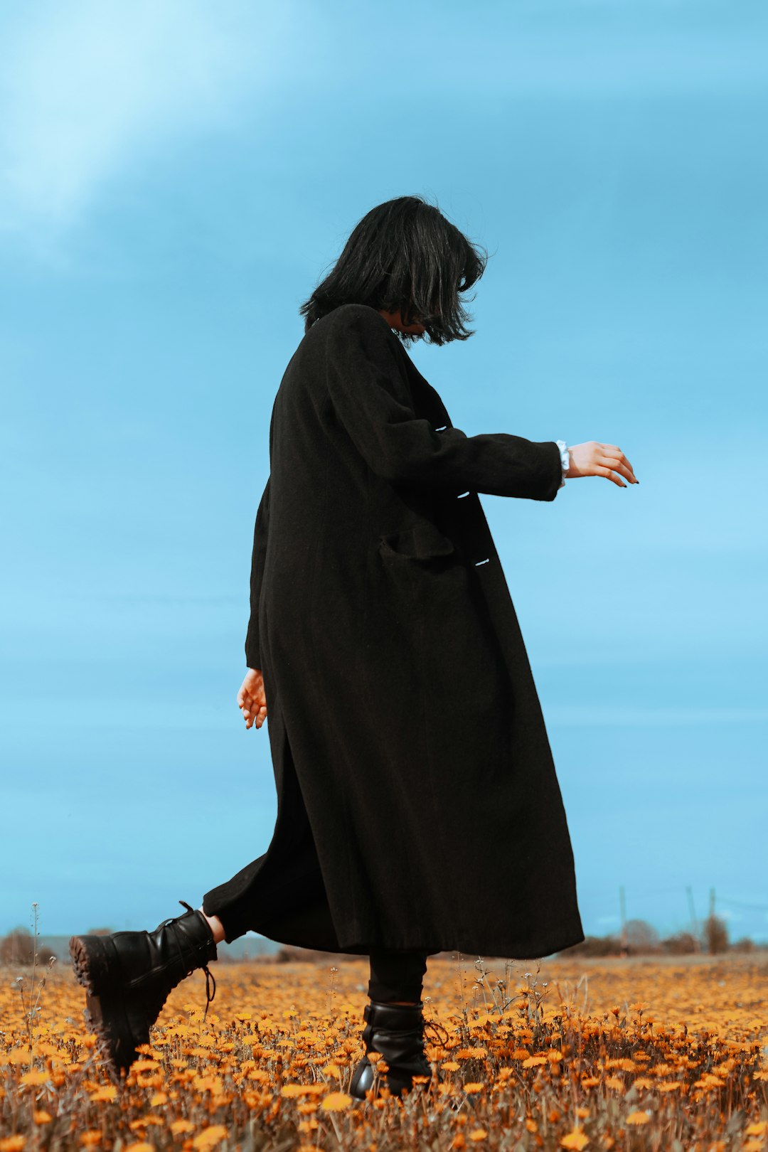 woman in black long sleeve dress standing on green grass field during daytime