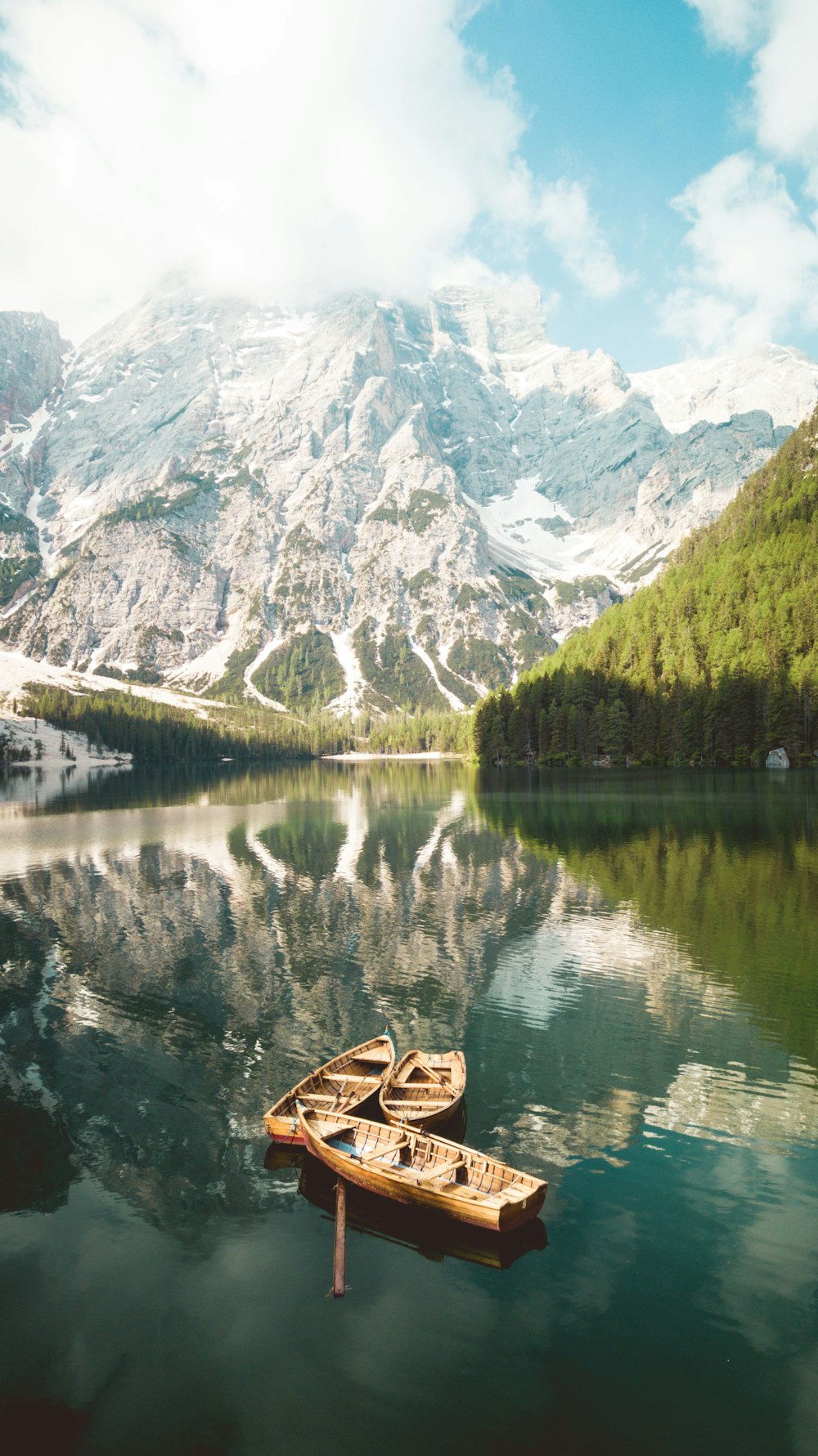 brown boat on lake near snow covered mountain during daytime