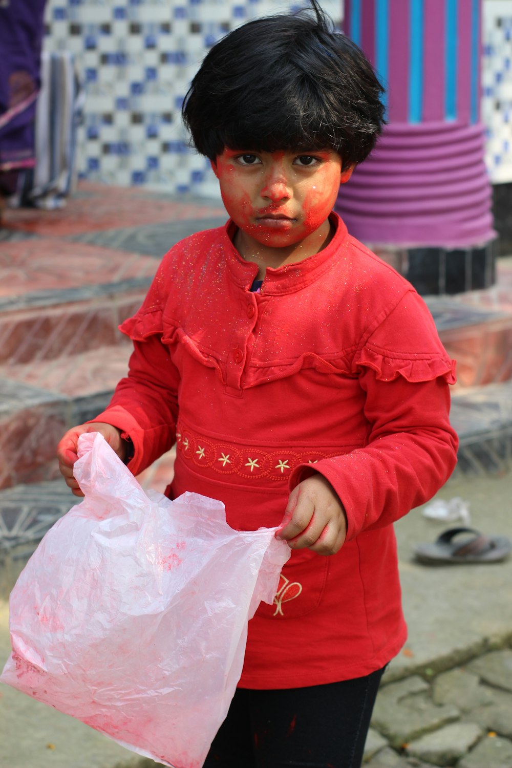 boy in red long sleeve shirt holding white plastic bag