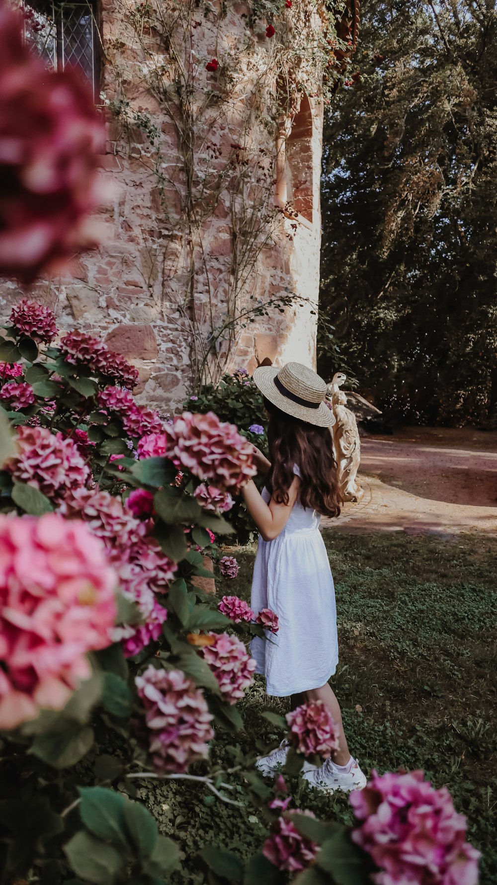 woman in white dress standing near pink flowers during daytime