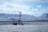 A solitary communication tower stands amidst a vast, snow-covered plain with distant mountains under a cloudy sky. The landscape appears desolate and expansive, with scattered power lines adding to the sense of isolation.