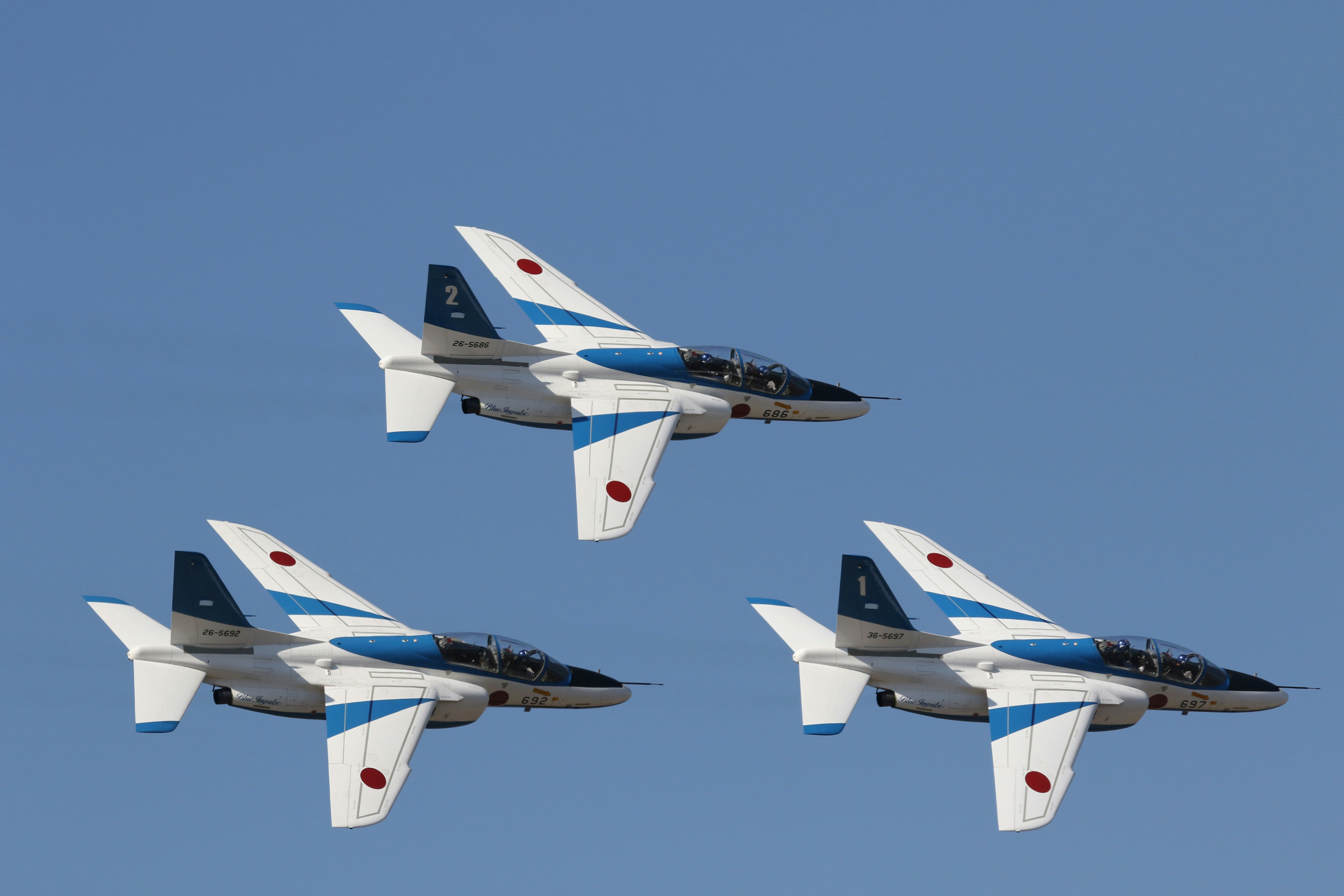 white and blue jet plane in mid air during daytime