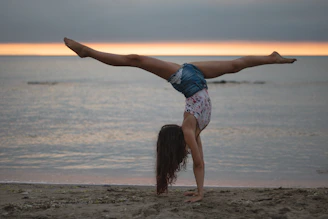 A confident young woman performing a dynamic calisthenics move outdoors at sunset.