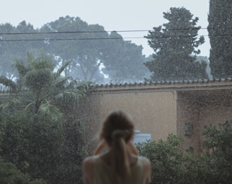 woman in white tank top standing near green plants during daytime