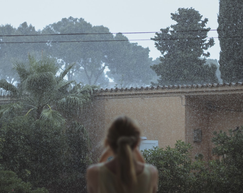 woman in white tank top standing near green plants during daytime