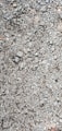 A close-up view of a gravel surface composed of variously sized stones and pebbles. The stones are mostly gray, with some variations in size and shape, including small and medium rocks.