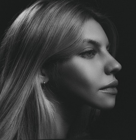 Black and white portrait of a model with sharp shadows highlighting facial features.