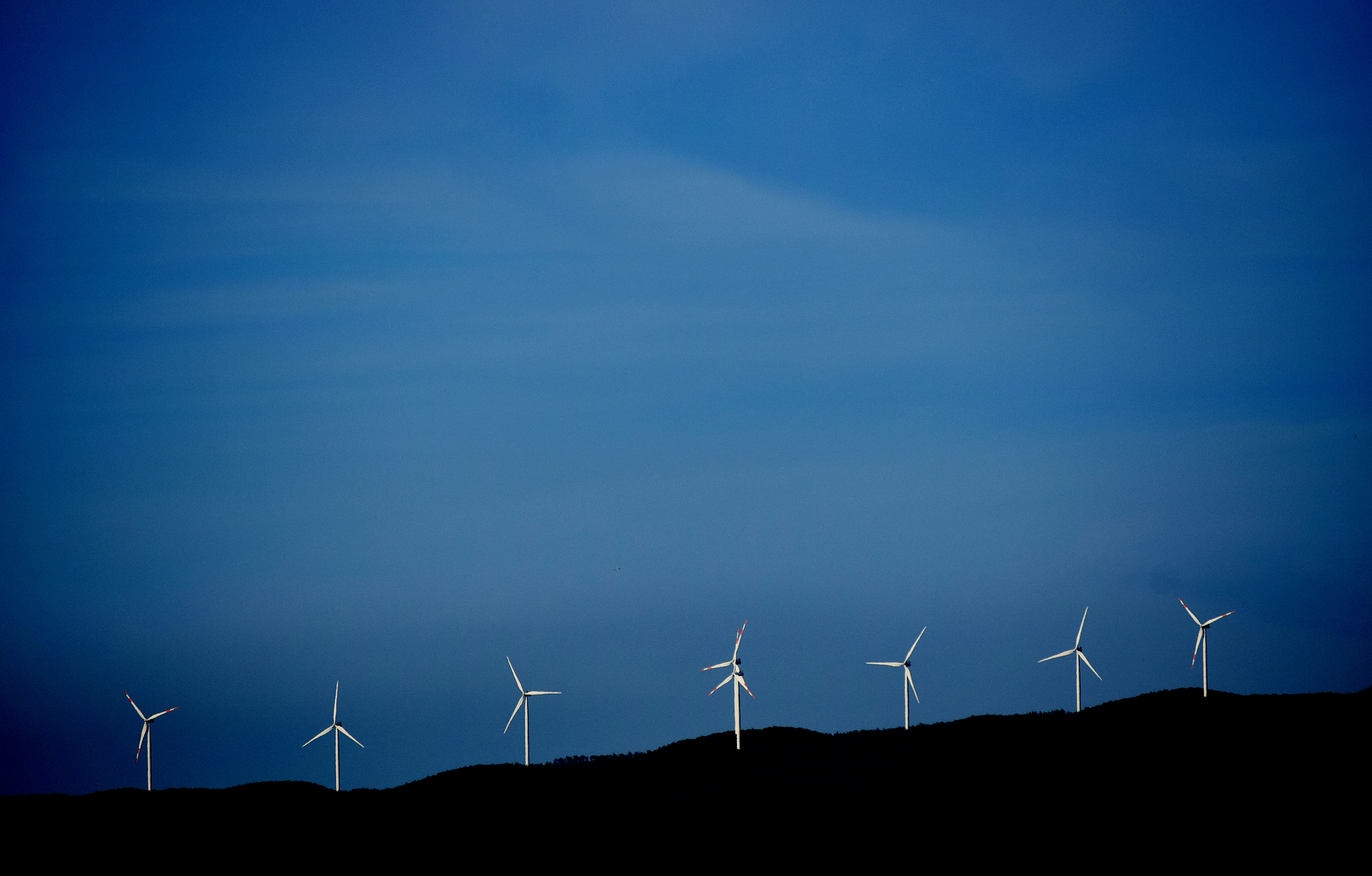 wind turbines on hill under blue sky