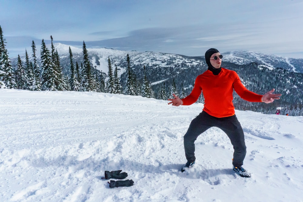 man in red jacket and black pants standing on snow covered ground