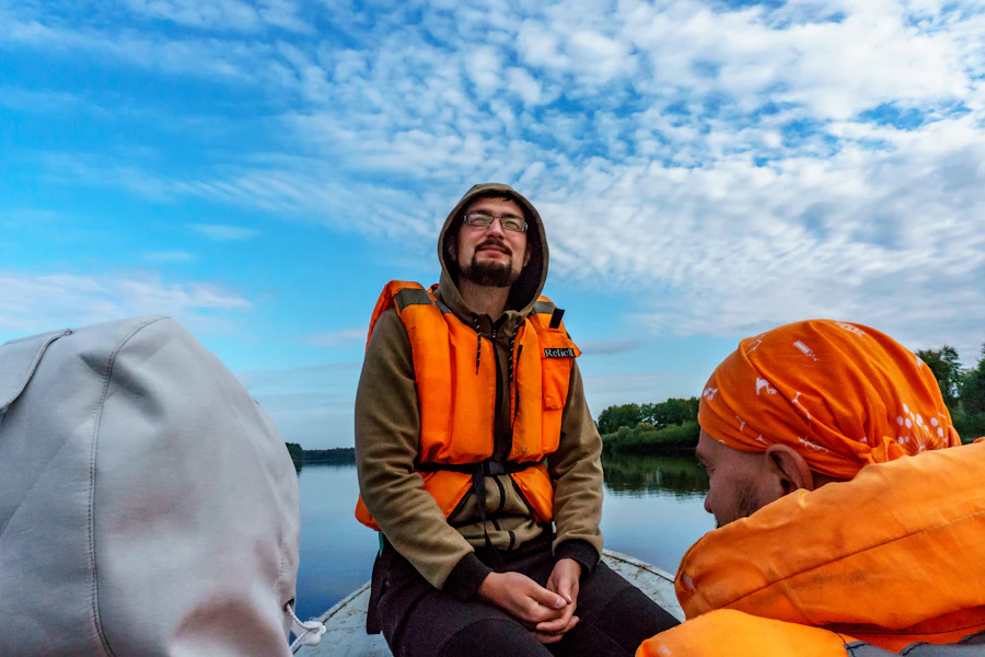 A guest wearing an orange safety jacket seated on a boat before departure