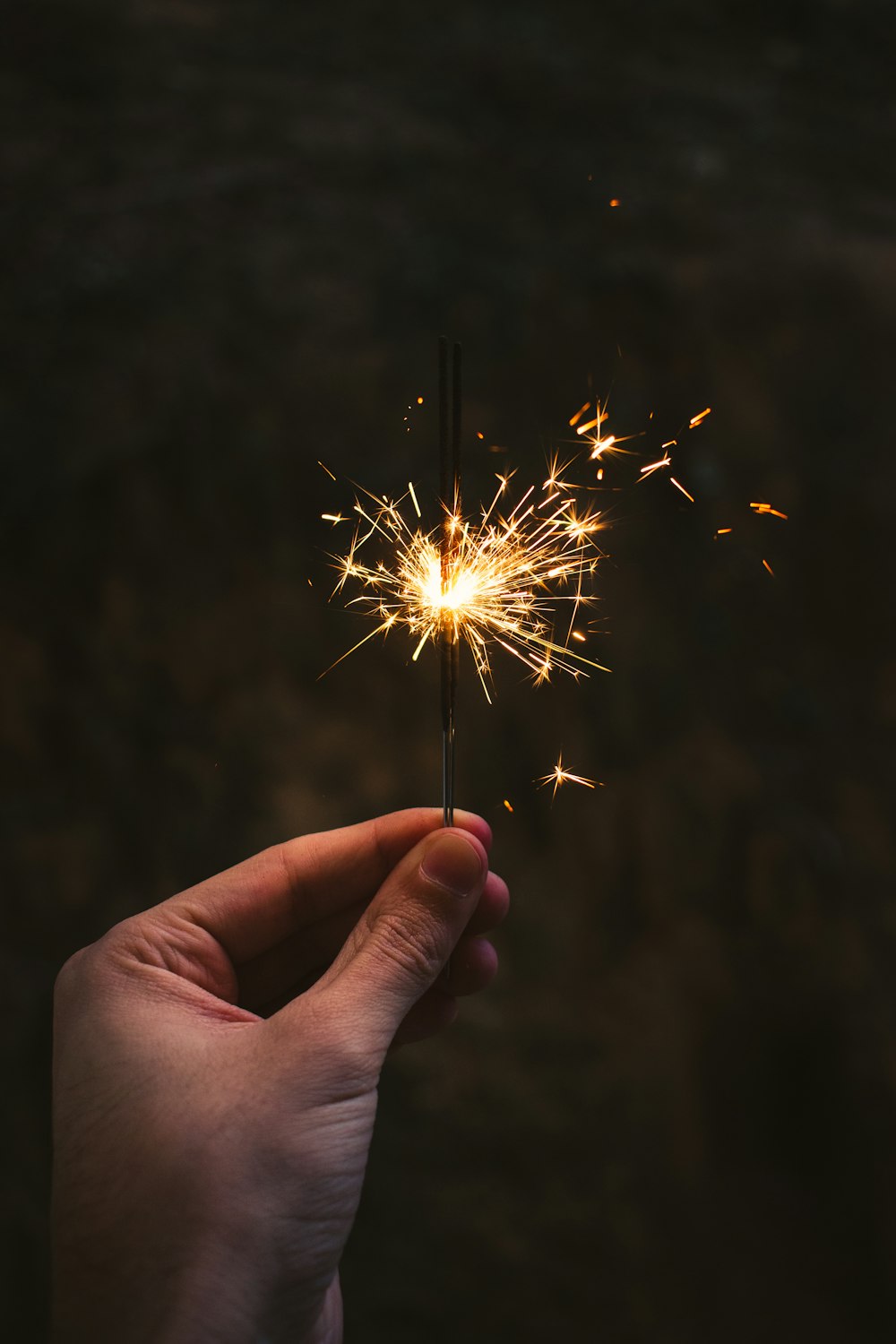 person holding sparkler in close up photography